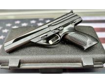 Semi‑automatic handgun with modern design and textured grip displayed on black case with blurred American flag background.